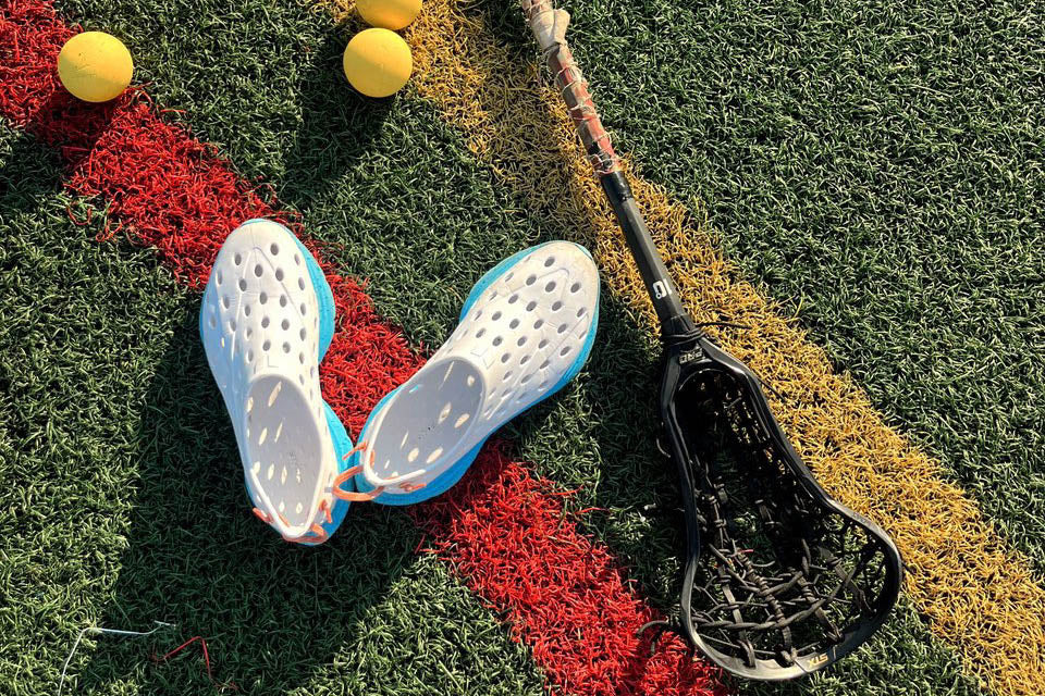 Lacrosse gear rests on multicolored artificial turf