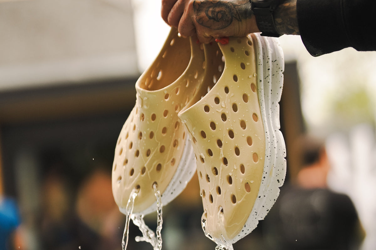 Hand holding wet foam clogs in a gym setting
