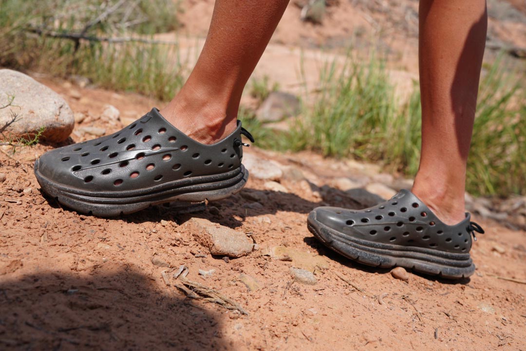 Person wearing black non-slip shoes walking across rocky desert terrain