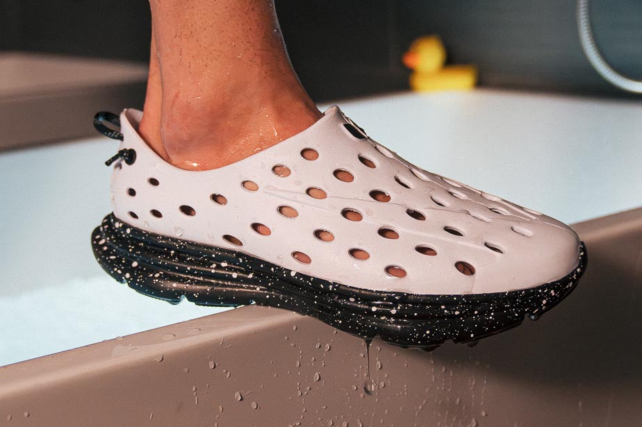 Side view of a light pink EVA shoe showcasing its textured black sole on a wet ledge