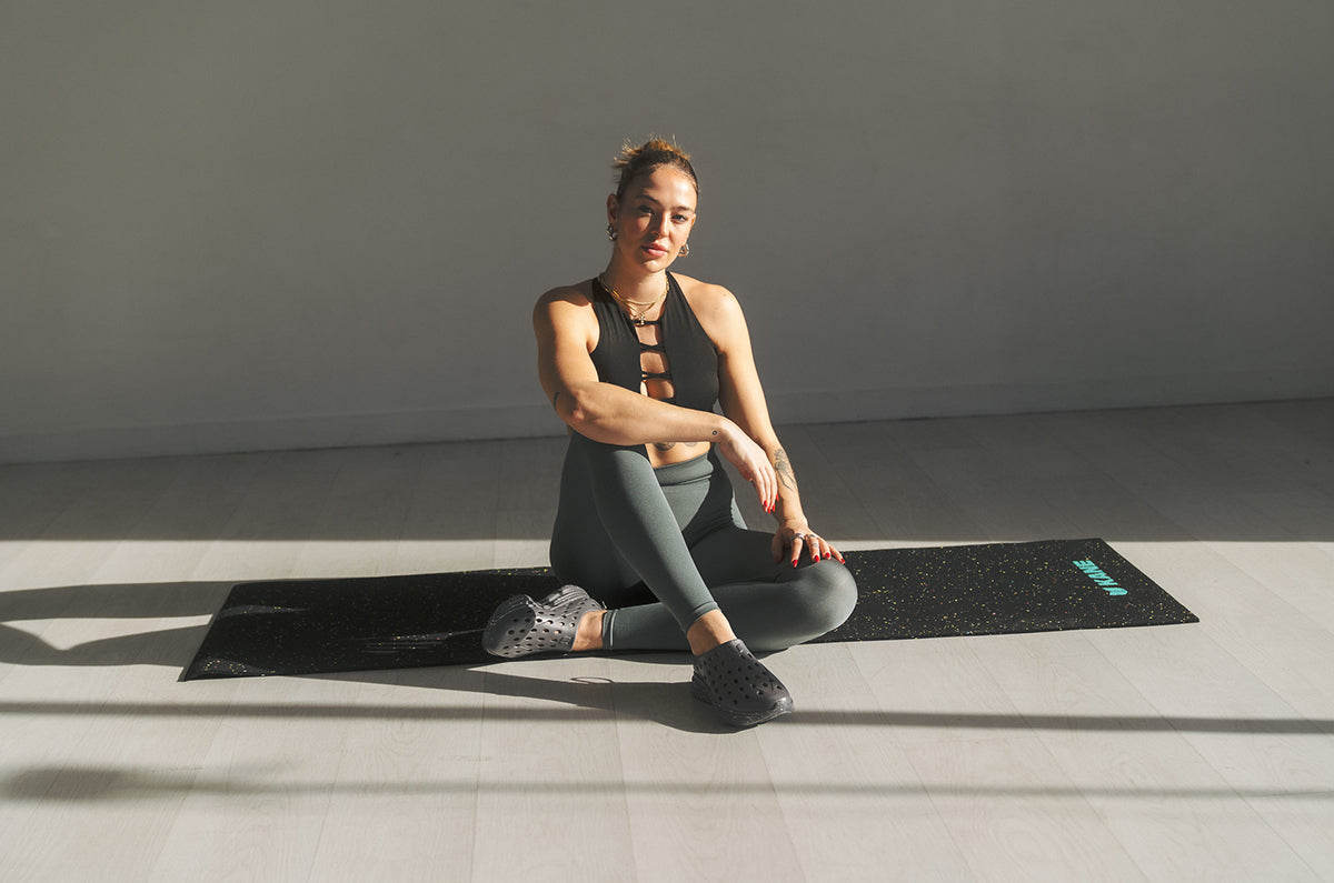 Woman seated on a yoga mat in a sunlit room