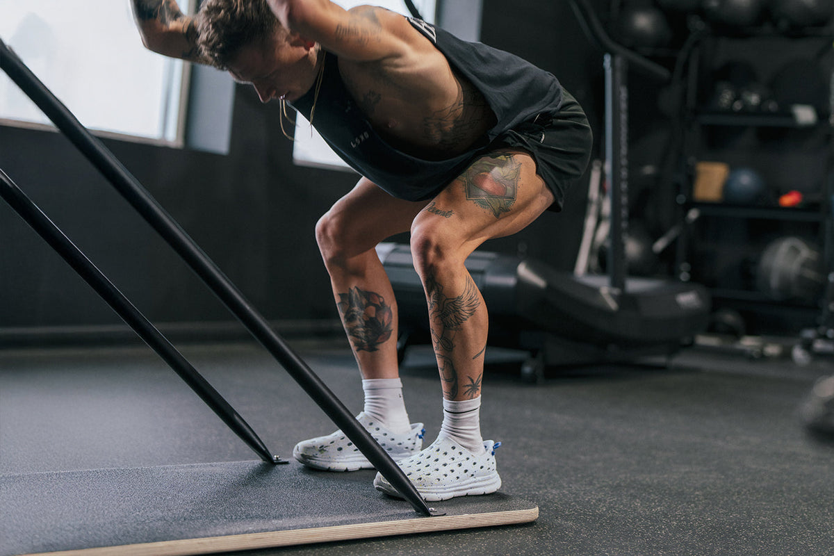 Athlete performing a deep squat on a slant board in a gym