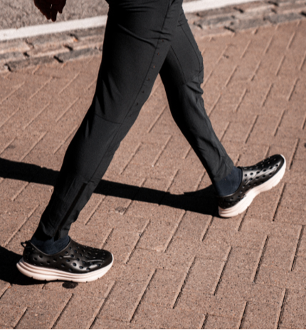 Closeup of a Cashier's shoes. He is walking to work wearing stylish Black Kane Revive recovery shoes. These shoes are supportive and comfortable, which are perfect for standing all day at a cash register.