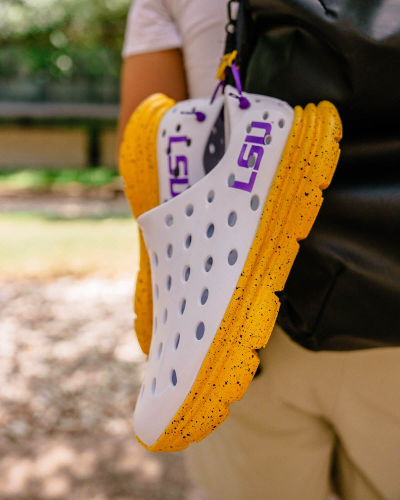 Closeup of Kane Revive LSU edition recovery shoes clipped to a backpack