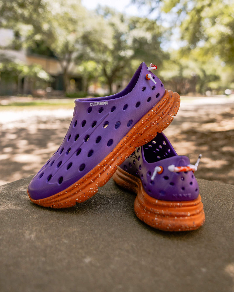 Stylish outdoor shot of Purple Clemson Kane Revive recovery shoes with a blurred background