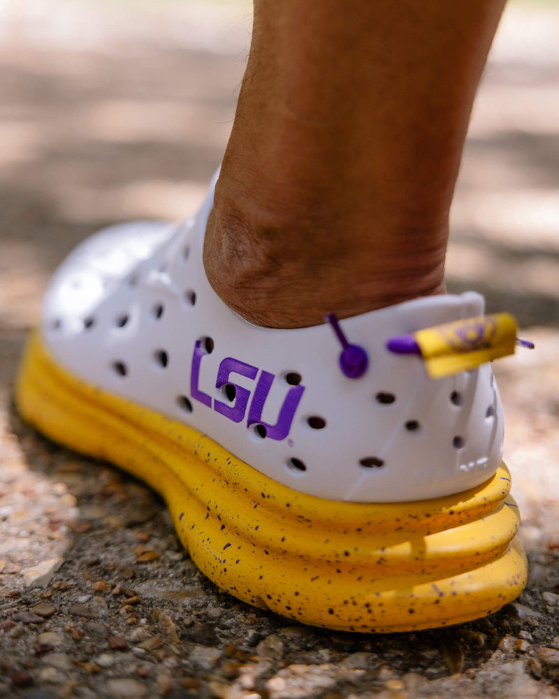 Closeup of LSU edition Kane Revive shoes against the sidewalk