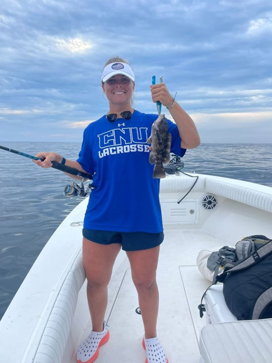 A woman smiling. Showing off the fish she caught while boating. Wearing Kane Revive shoes with non-slip grip which is perfect for boats.