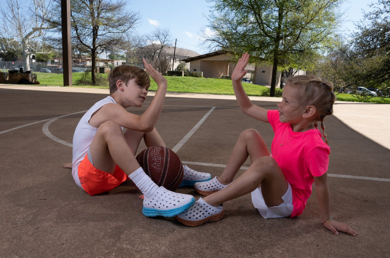 Kids at the basketball court high-fiving each other because they got cool new Kane Revive recovery shoes