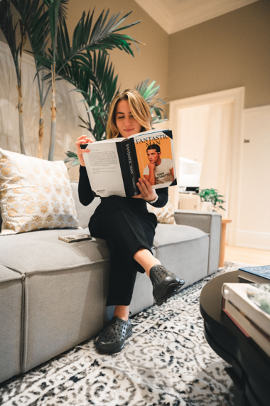 A librarian enjoying a book at the sofa. Wearing her stylish and comfortable Kane recovery shoes.