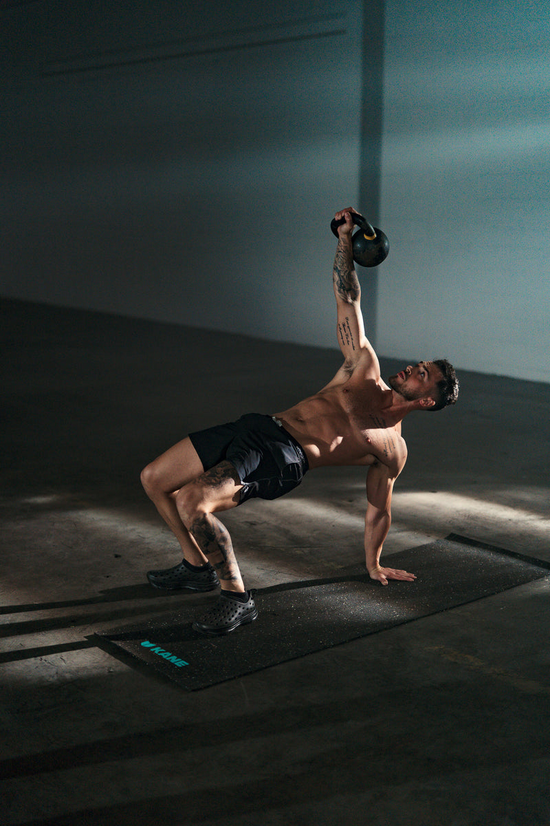 A man exercising wearing Black Kane Revive recovery shoes, exercising on his Kane Renew yoga mat.
