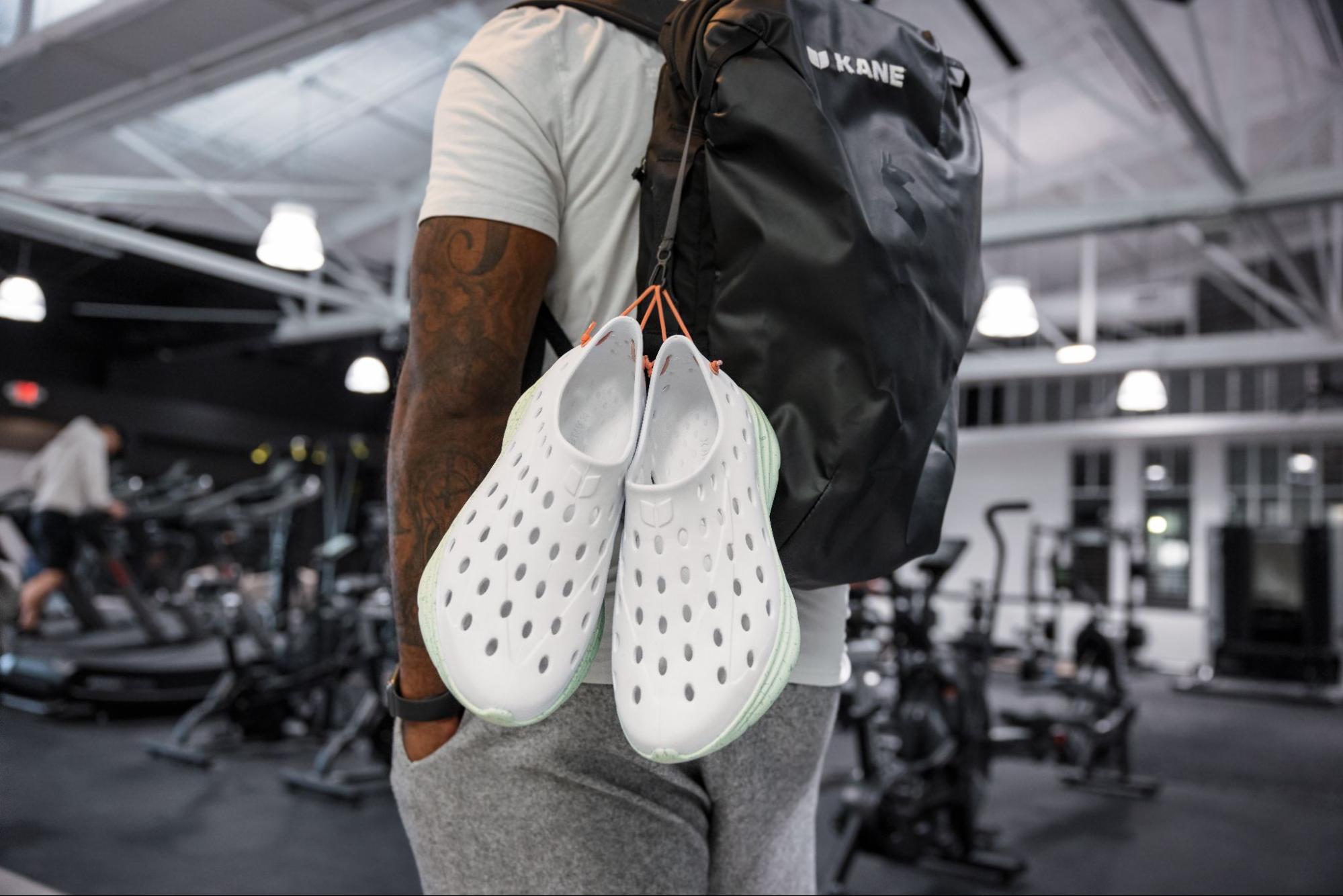 Close-up of Kane Revives clipped to a backpack. The back of the shoe has holes for straps, making it perfect for equipping to a backpack.